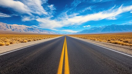 Naklejka premium A vast, endless road stretching into the horizon, surrounded by towering mountains.