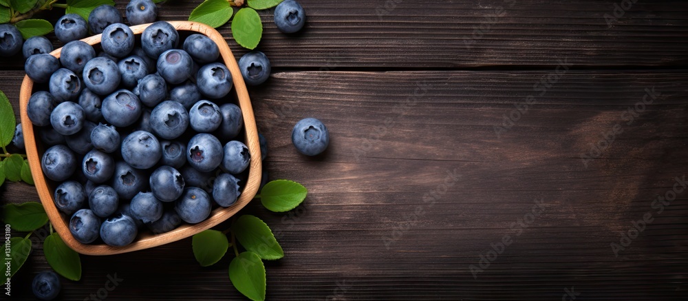 Poster fresh blueberries arranged in a wooden bowl on a dark wooden surface with green leaves to the side a