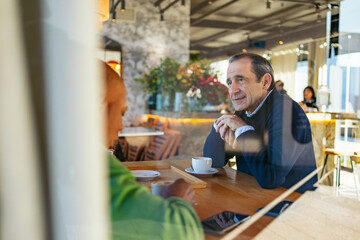 Middle aged friends conversing during casual coffee meetup at rustic cafe