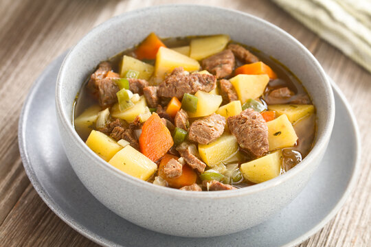Vegan soup or stew made with vegetable potato, onion, garlic, carrot, green pepper and soy meat chunks, served in bowl (Selective Focus, Focus in the middle of the image)