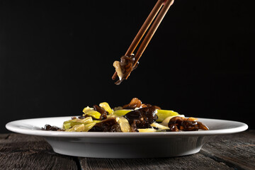 Stir-fried Celery with Wood Ear Mushrooms on black background. Food concept