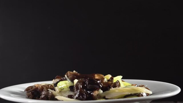 Stir-fried Celery with Wood Ear Mushrooms on black background. Food concept