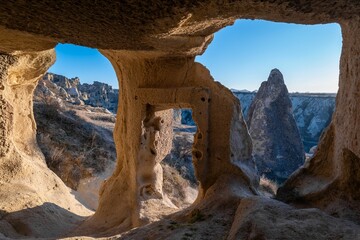 View from a cave in Cappadocia, Turkey, showcasing unique rock formations under a clear blue sky.