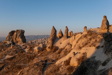 View of Cappadocia's unique rock formations under a clear blue sky during sunset