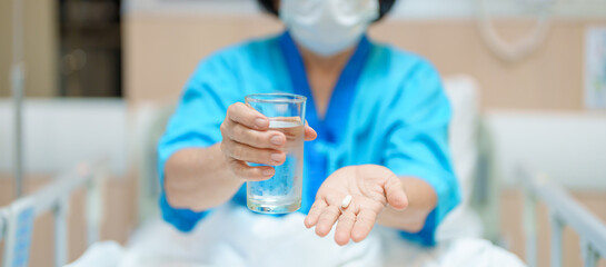 Elderly asian Patient Woman hold pill and glass of fresh water. Female Senior take medicine tablets in hospital. Influenza, Fever, illness, treatment, Insurance, Healthcare, medical and Medicine day