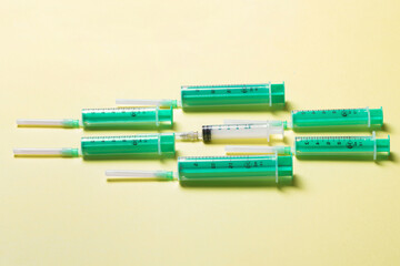 Obraz premium Top view of medical syringes with needles at yellow background with copy space. Injection treatment concept