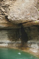 The waterfall flows down the cliff and falls into the river. Natural landscape