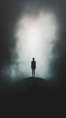 A person stands at the top of a hill with a cloudy sky in the background, providing a sense of isolation and contemplation