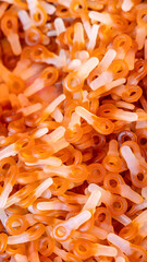 Background made of gummy candies shaped like small keys with a translucent orange and white color featuring a glossy soft texture and overlapping smooth forms
