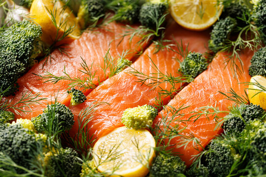 Close-up view of raw salmon fillets with broccoli and lemon, focus on the center