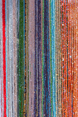 Obraz premium Background of multicolored bead strands arranged in vertical rows shimmering surfaces reflect light