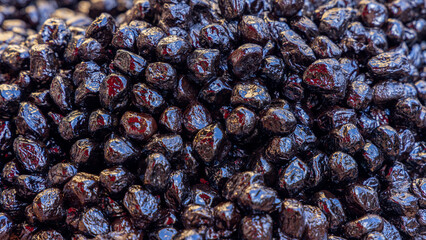 Background of black wrinkled olives with glossy surfaces deep dark tones and slightly shriveled texture
