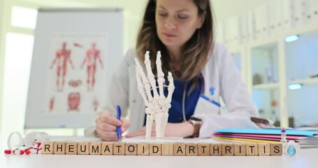 A healthcare professional examines a detailed model of a human hand to discuss the complexities of rheumatoid arthritis