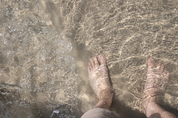 A person's feet are in the water, with the water being a light brown color
