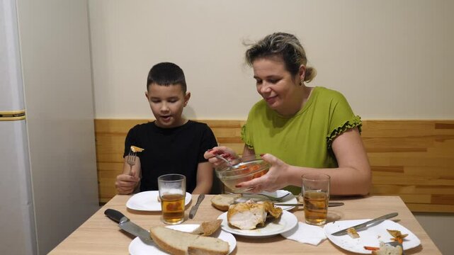 Mother and son having dinner with chicken and salad.
