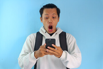 Asian male student college looking at screen mobile phone with surprised expression