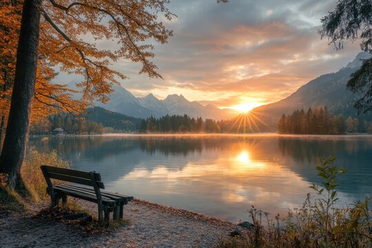 Empty bench observing stunning autumn sunrise over lake and mountains