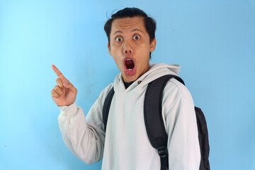 Asian male student college pointed upwards with a shocked expression