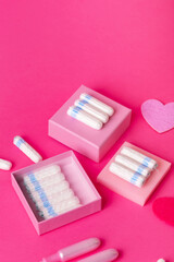 Fototapeta premium Many menstrual hygiene tampons from above on pink background in beautiful composition. Soft cotton absorbent menstrual tampons for women during menstruation. Feminine hygiene. 