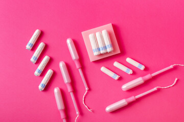 Many menstrual hygiene tampons from above on pink background in beautiful composition. Soft cotton absorbent menstrual tampons for women during menstruation. Feminine hygiene. 