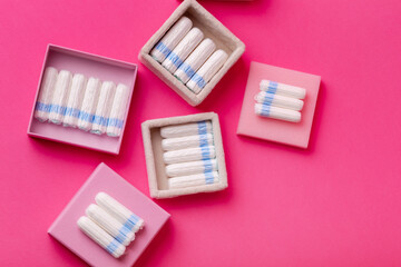 Many menstrual hygiene tampons from above on pink background in beautiful composition. Soft cotton absorbent menstrual tampons for women during menstruation. Feminine hygiene. 