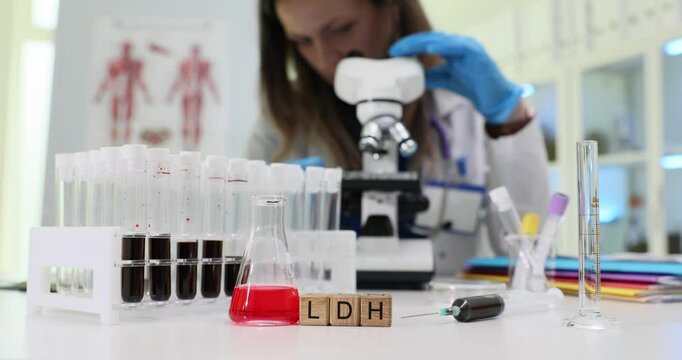 A scientist examines slides under a microscope in a modern lab with test tubes and research equipment