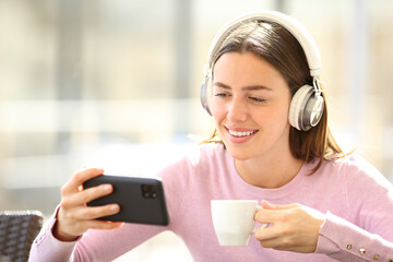 Happy woman drinking coffee in a bar watching media online
