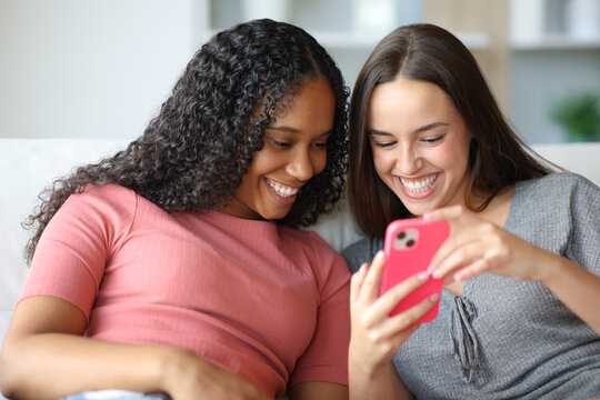Happy interracial friends checking cell phone content