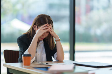 Stressed businesswoman holding head in hands at office desk