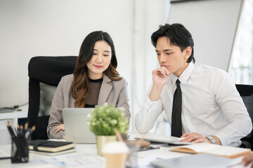 An Asian female executive is discussing marketing plans with a senior officer in a conference room.