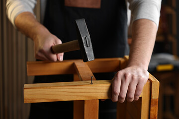 Carpenter repairing wooden stool in workshop, closeup
