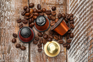 Coffee capsules and beans on wooden table, flat lay
