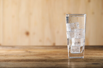 Refreshing soda water with ice cubes in glass on wooden table. Space for text