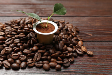 Coffee capsule with leaves and beans on wooden table, closeup. Space for text