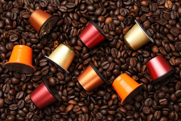 Coffee capsules on roasted beans, flat lay