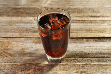 Sweet soda water with ice cubes in glass on wooden table, closeup