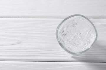 Refreshing soda water with ice cubes in glass on white wooden table, top view. Space for text