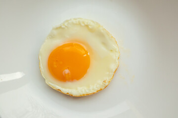 Fried egg on white dish close up