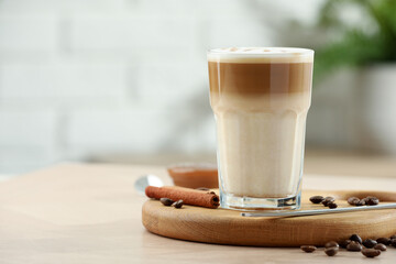 Tasty latte macchiato in glass on wooden table, closeup. Space for text