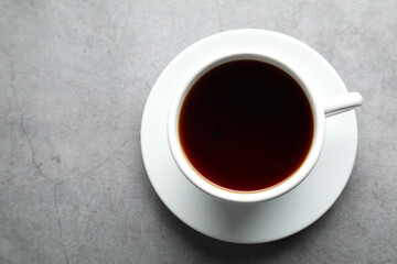 Refreshing black tea in cup on grey textured table, top view. Space for text