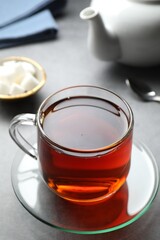 Refreshing black tea in cup on grey table, closeup