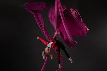 Girl performing aerial silk acrobatics in a vibrant studio setting