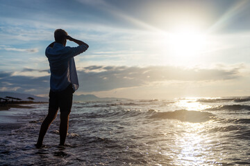 Fototapeta premium Silhouette of one man on tropical beach during picturesque orange sunset. People, vacation happiness