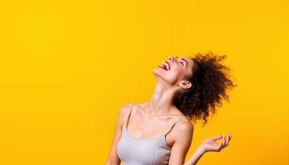 Obraz premium Joyful woman laughing against bright yellow backdrop, happiness concept
