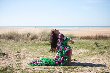 Woman dancing flamenco in a white dress with floral print and ruffles, sitting on an old wooden...