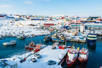 Obraz premium Boat activity in the icy Port of Ilulissat showcasing the vibrant town and colorful buildings under a clear sky
