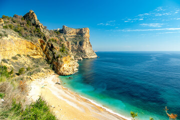 Obraz premium Turquoise waters and golden cliffs at Costa Blanca’s hidden beach, Moraig