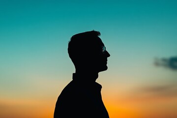 A man is standing in the middle of a blue sky with a sunset in the background