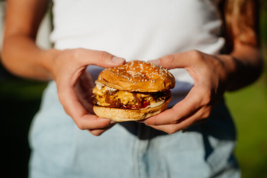 Smashed cheeseburger with sesame bun outdoors in summer