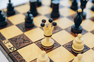 Antique handmade carved chess.Chess pieces on a high-quality chess board on a bright table in a country cottage before a match.Chessboard with black and white carved pieces.Vintage souvenir
